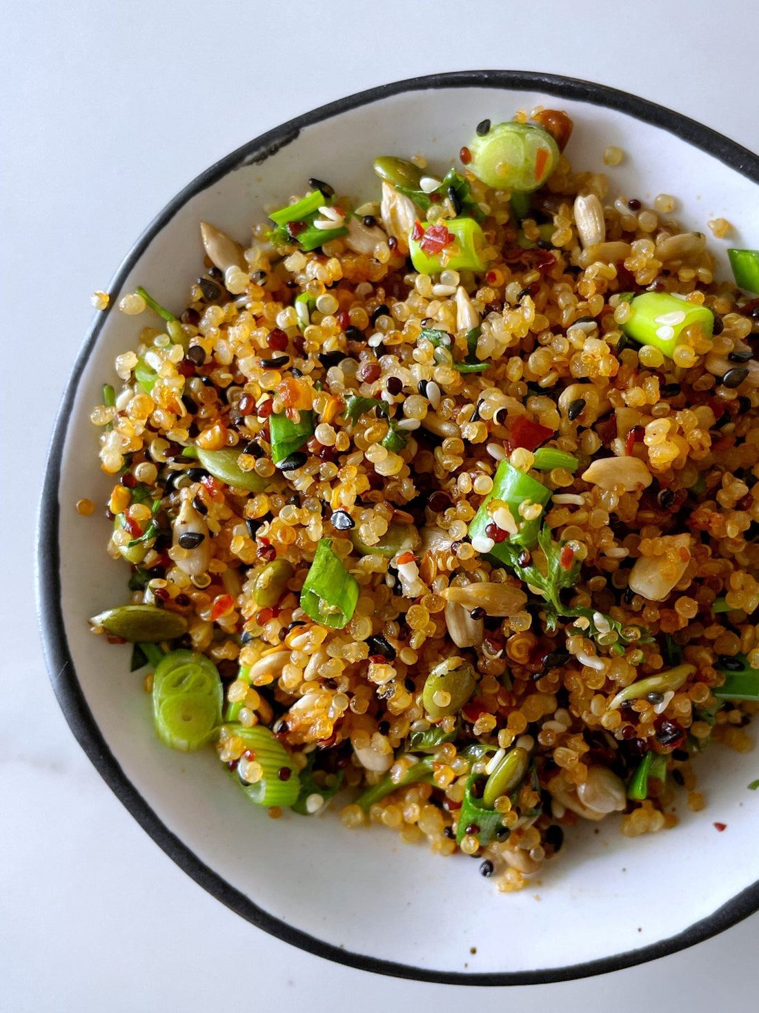 Ingredients for superfood fried “rice” including cooked quinoa, seeds, chili oil, coconut aminos, and fresh herbs