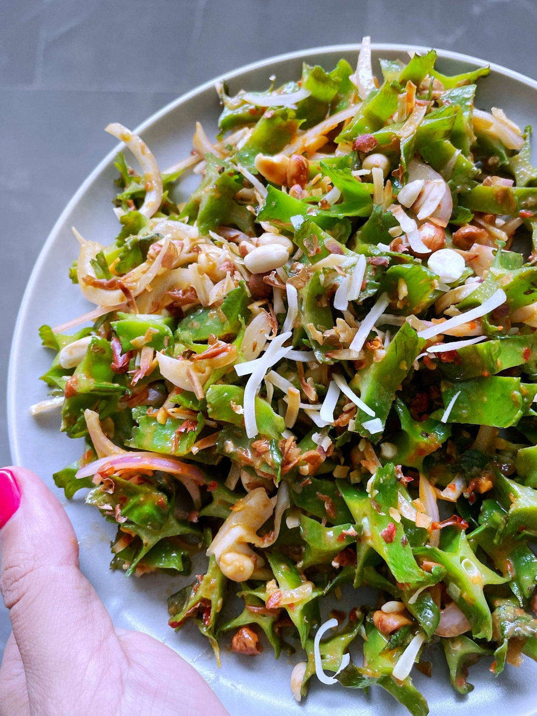 Close-up of Thai-style green bean salad tossed in sambal dressing with herbs and crunchy peanuts